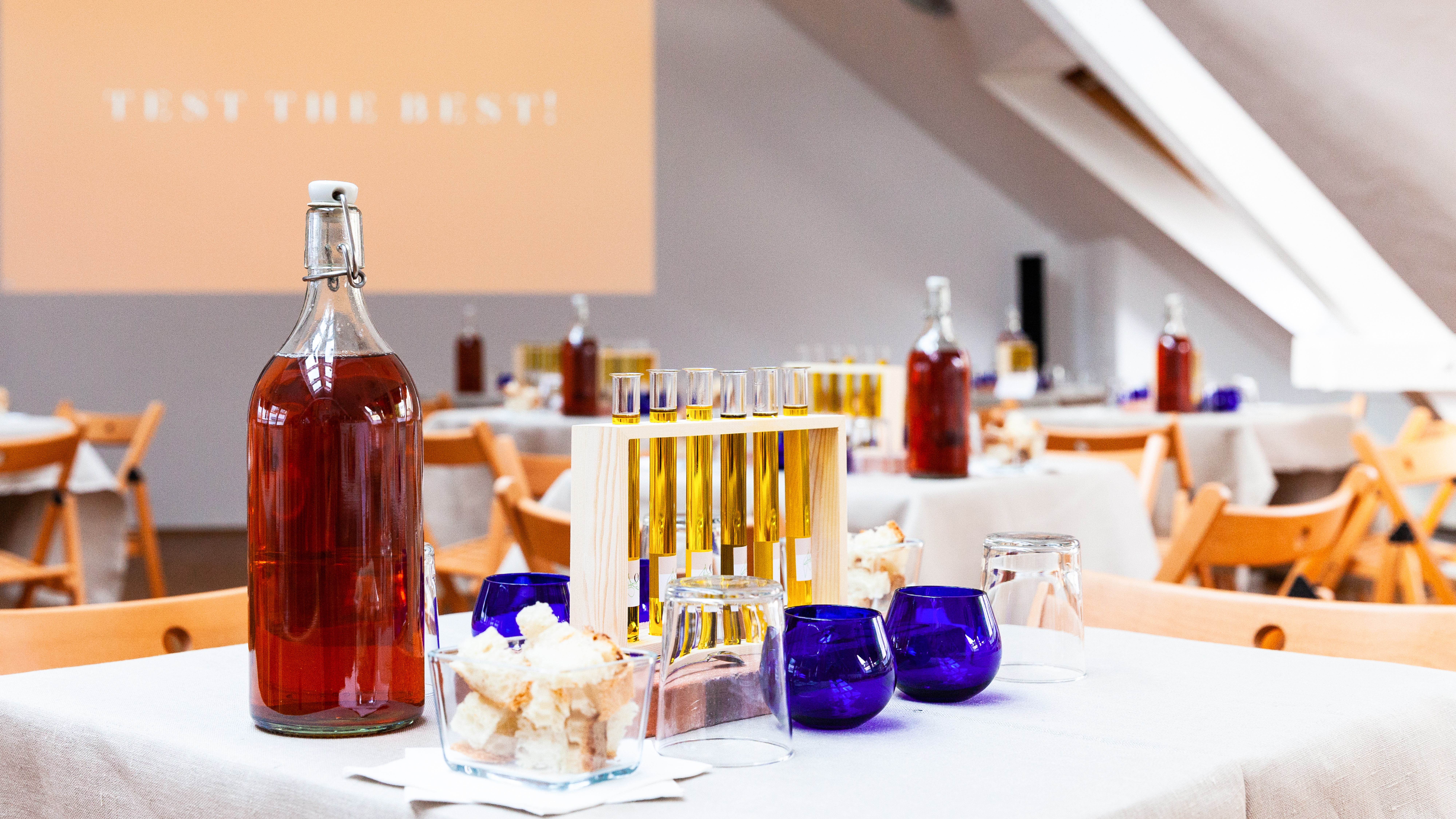 VISUELL Blogbeitrag: Event unterm Dach– das Olivenöl-tasting: Auf einem Tisch stehen verschiedene Arten Olivenöl in Reagenzgläsern