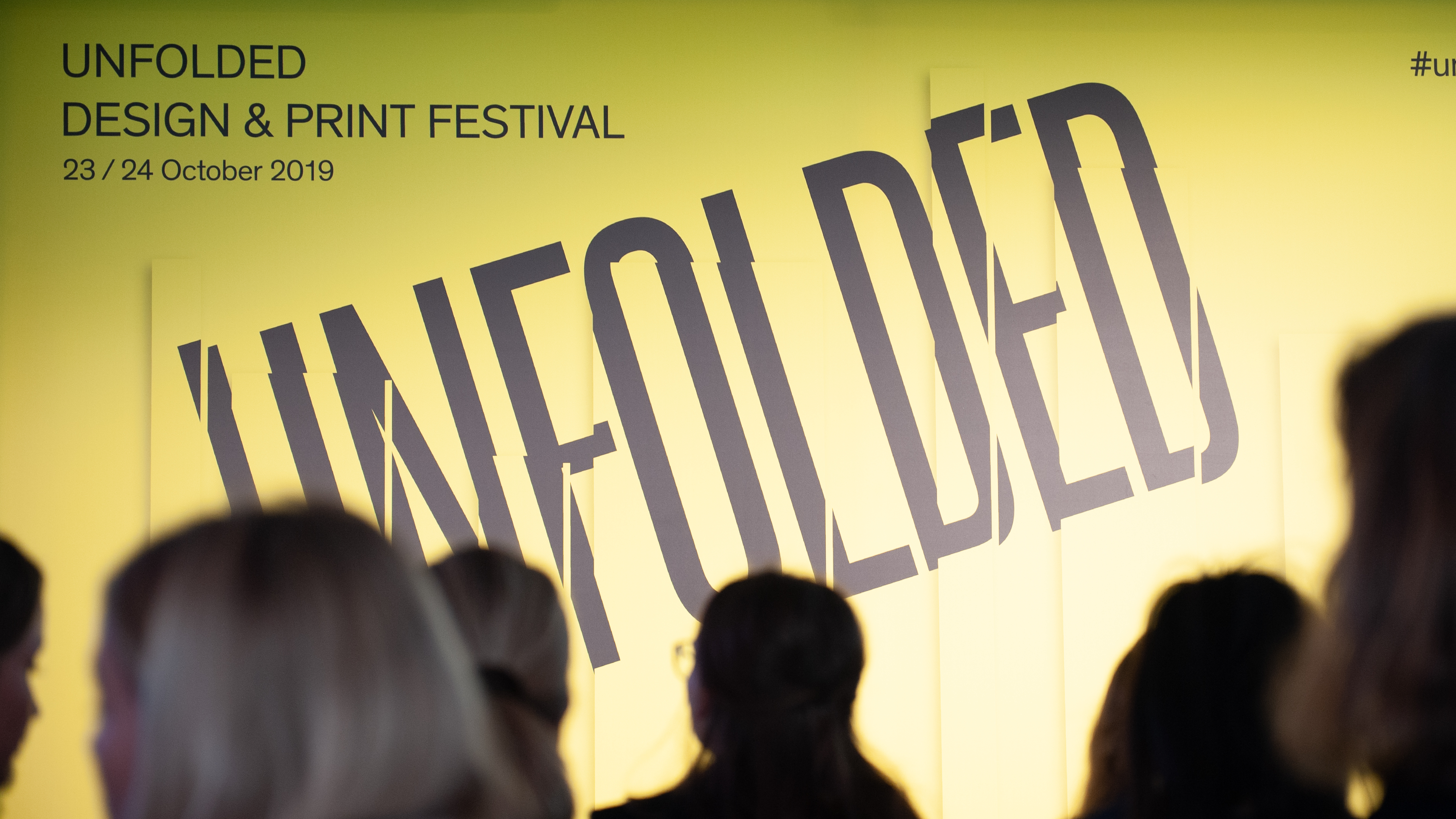 VISUELL Blogbeitrag: Auf Weiterbildung in Innsbruck und München erleben wir extreme Dinge VISUELL Blogbeitrag: Weiterbildung in Innsbruck und München: Ein gelbes Plakat mit der Aufschrift UNFOLDED - Design und Print Festival