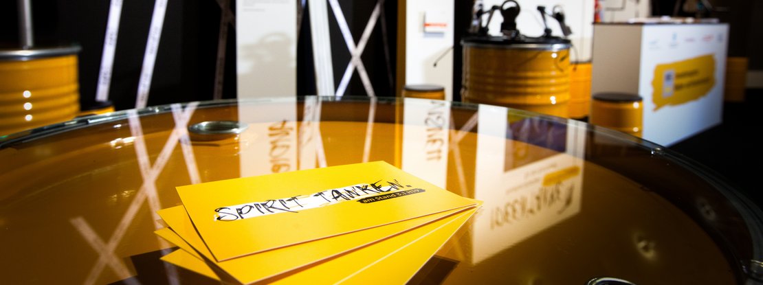 VISUELL Szenografie: Messestand Ideentanke MFG: Detailaufnahme von vier gelben Flyern mit der Aufschrift Spirit tanken