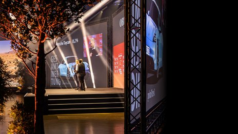 VISUELL Szenografie: BEST CARS 2023: Eine große Bühne, auf der zwei Männer stehen umgeben von Pflanzen