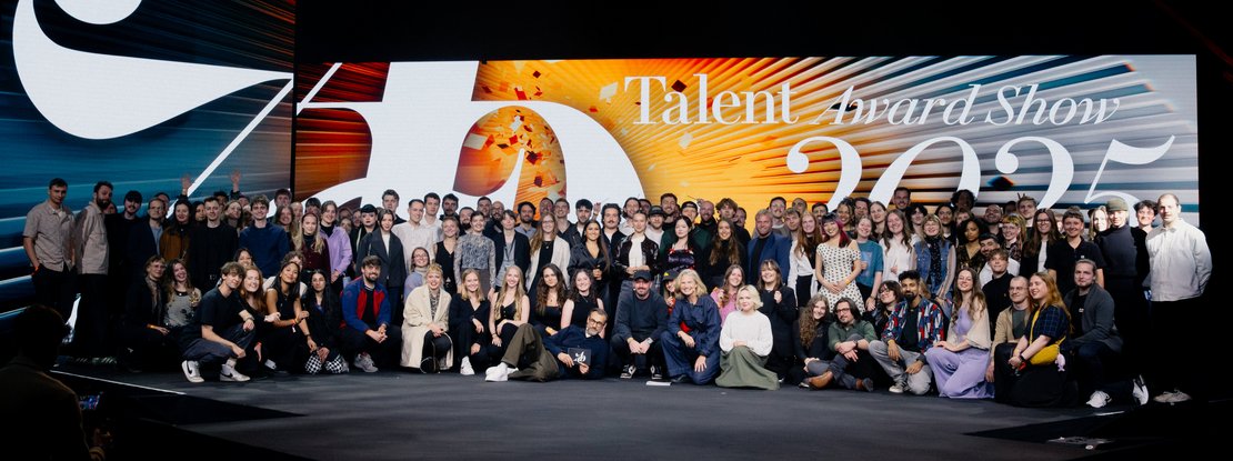VISUELL Blogbeitrag: ADC Talent Award 2025: Gruppenfoto der Nachwuchstalente auf der großen Festivalbühne, vor leuchtender Medienwand mit der Aufschrift „Talent Award Show 2025“.