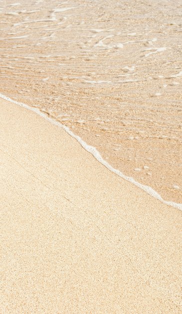 VISUELL Kommunikationsdesign: Corporate Design: Detailaufnahme eines Sandstrands mit ankommenden, leichten Wellen.