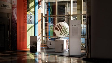 VISUELL Szenografie: Ausstellungsrundgang: Übersicht der Ausstellung, mit Stoffbannern und Globus für die Geschichte des Verlags 
