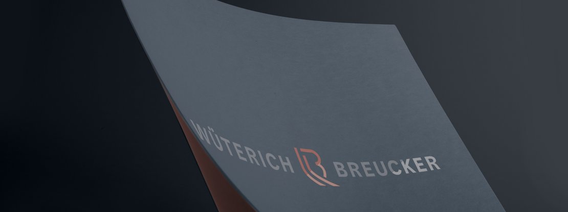 VISUELL Kommunikationsdesign: Corporate Design: Nahaufnahme der mit Heißprägefolie veredelten Wort-Bild-Marke auf dunkelblauem Papier
