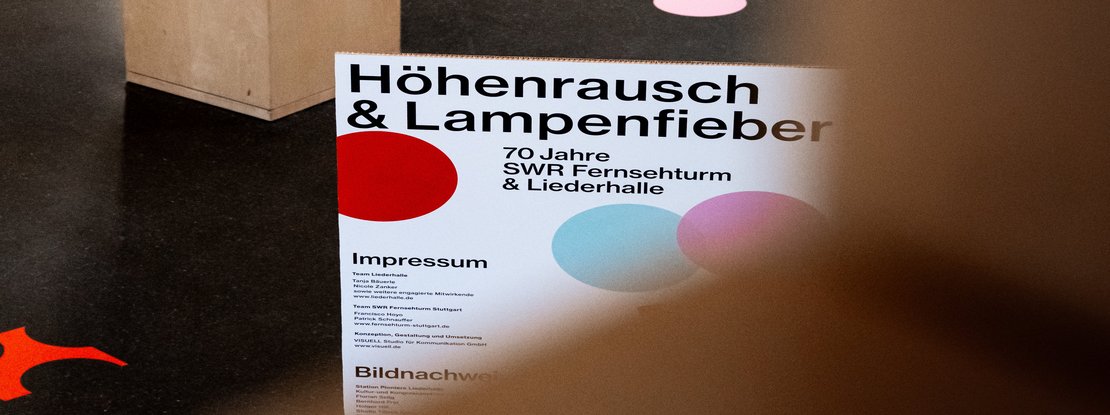 Szenografie: Jubiläumsausstellung: 70 Jahre Fernsehturm und Liederhalle: Titelmotiv der Ausstellung „Höhenrausch und Lampenfieber“ mit typografischem Keyvisual und farbigen Konfettipunkten als verbindendes Gestaltungselement der Jubiläumsinszenierung.