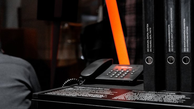 VISUELL Szenografie: Sonderausstellung: Anti Anti 2.0: Hörstation mit Telefonhörer; audiovisuelle Angebote machen Mechanismen von Verschwörungserzählungen erfahrbar.