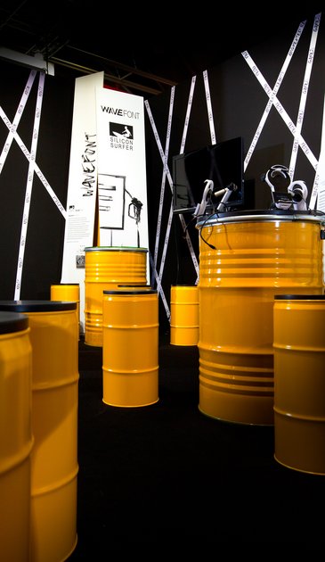 VISUELL Szenografie: Messestand Ideentanke MFG: Gelbe Tonnen und typografische Banner im Hintergrund