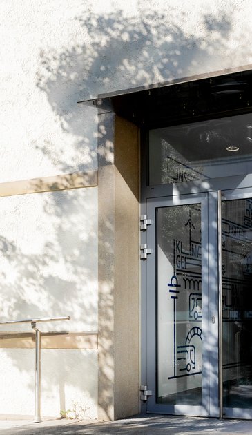 VISUELL Kommunikationsdesign: Wandgrafiken Landeshauptstadt Stuttgart: Eingangsbereich mit Glastür, auf der grafische Elemente und Icons der Wandgestaltung nach außen sichtbar sind.