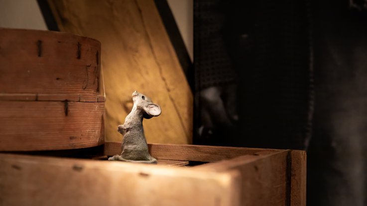 VISUELL Scenography: Permanent exhibition at Hornmoldhaus: Detail of a small mouse figure placed between historic wooden boxes and half-timbered beams. The playful element complements the atmospheric workshop setting in the historic room.