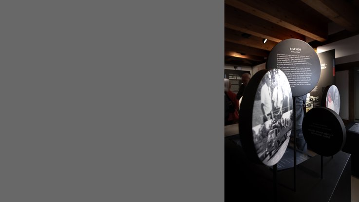 VISUELL Scenography: Spatial staging with round, free-standing image and text carriers on the history of the city in the Hornmoldhaus. Historical photographs and biographical content – including Bishop Gündlach – are presented in a multi-layered, walk-in installation and invite visitors to engage with the subject matter on a personal level.