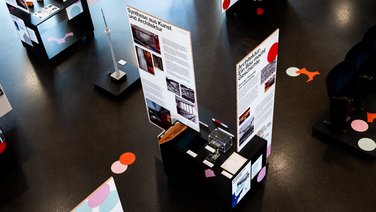 VISUELL Szenografie: Jubiläumsausstellung: 70 Jahre Fernsehturm und Liederhalle: Ansicht von oben der Ausstellung mit Grafikträgern, Exponaten und modularen Möbeln; Konfettipunkte strukturieren den Raum als durchgängiges Keyvisual.