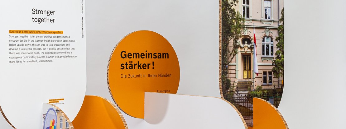 VISUELL Scenography: Robert Bosch Stiftung GmbH travelling exhibition: a panoramic close-up of a modular exhibition element featuring organically curved orange panels; the image shows text and a cityscape