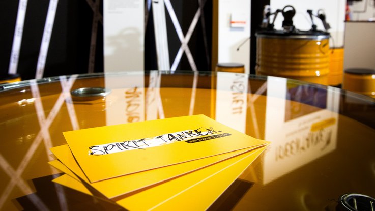 VISUELL Szenografie: Messestand Ideentanke MFG: Detailaufnahme von vier gelben Flyern mit der Aufschrift Spirit tanken