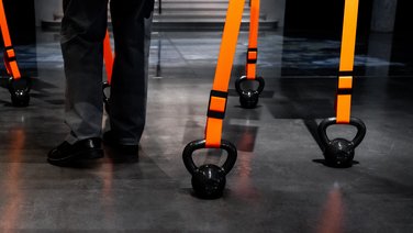 VISUELL Szenografie: Sonderausstellung: Anti Anti 2.0: Detailansicht mehrerer orangefarbener Bänder mit Gewichten gespannt;