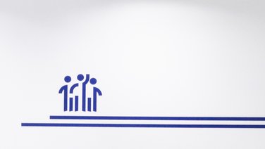 VISUELL Kommunikationsdesign: Wandgrafiken Landeshauptstadt Stuttgart: Reduziertes Iconmotiv mit stilisierten Personen als Symbol für Gemeinschaft und Zusammenarbeit.