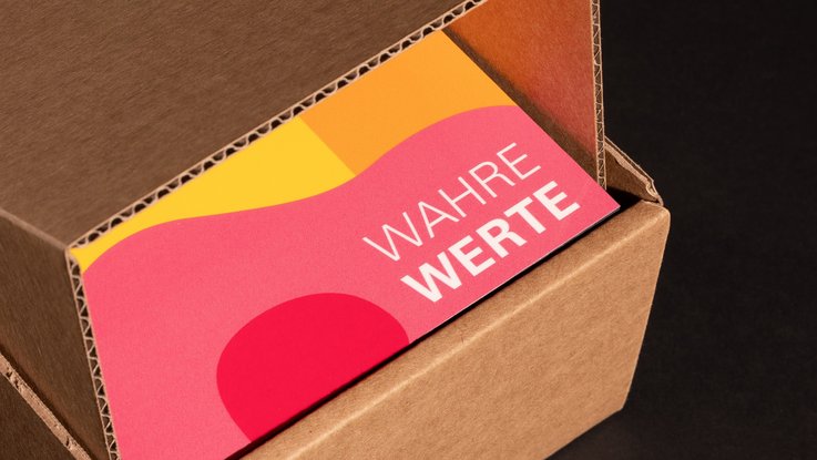 VISUELL Kommunikationsdesign: Aufgeklappter Karton mit Blick auf die farbige Denkmalplakette des Landesamts für Denkmalpflege mit dem Schriftzug „Wahre Werte“
