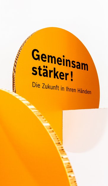 VISUELL Szenografie: Wanderausstellung „Common Grounds – Über Grenzen mitgestalten“ für die Robert Bosch Stiftung GmbH VISUELL Szenografie: Wanderausstellung Robert Bosch Stiftung GmbH: Detailansicht einer vertikalen Ausstellungsstele mit abgerundeter Form und orangefarbener Fläche; zentrales Textelement „Gemeinsam stärker! Die Zukunft in Ihren Händen“.