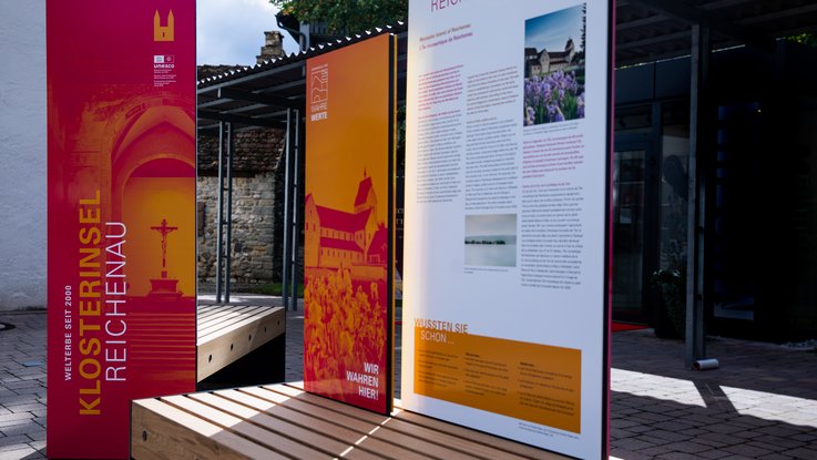 VISUELL Szenografie: Wahre Wunderbänke: Nahaufnahme der Sitzbänke mit Informationstafeln mit plakativer Typografie und aufmerksamkeitsstarken Bildern sowie Informationstexten in Deutsch, Englisch und Französisch