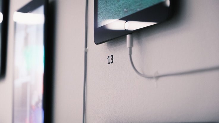 VISUELL Blogbeitrag: ADC Talent Festival 2025 „Goldenes Konfetti – Silberner Nagel“ VISUELL Blogbeitrag: ADC Talent Award 2025: Detailaufnahme der Installation „353“ mit Tablet und der Zahl 13 an der Wand, technische Inszenierung der Videoinhalte.