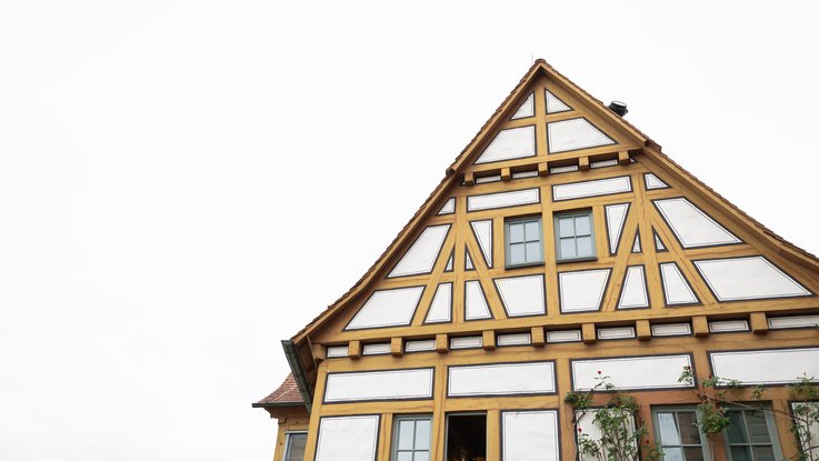 VISUELL Scenography: Permanent exhibition Hornmoldhaus: Exterior view of the historic half-timbered building with white plastered infill and ochre-coloured wooden framework. The steep gable with symmetrical window arrangement characterises the striking architecture of the city museum.