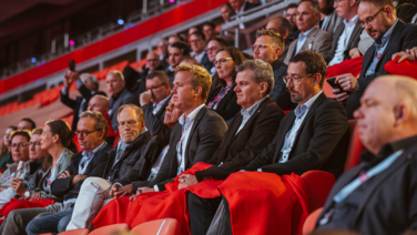 VISUELL Szenografie: Event „NEXT LEVEL“: Die Zuschauenden sitzen auf der Tribüne der Allianz Arena und folgen dem Vortrag auf der Bühne.