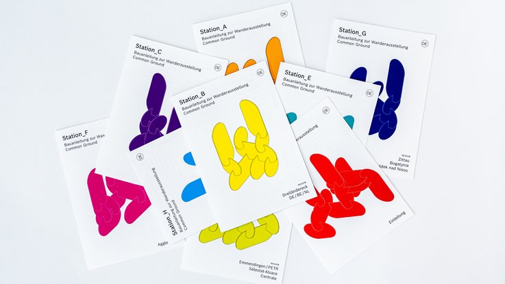 VISUELL Szenografie: Wanderausstellung „Common Grounds – Über Grenzen mitgestalten“ für die Robert Bosch Stiftung GmbH VISUELL Szenografie: Wanderausstellung Robert Bosch Stiftung GmbH: Mehrere sich überlappende Blätter zeigen abstrahierte Varianten der späteren Ausstellungselemente; sie sind Gelb, Blau, Rot und Violett;