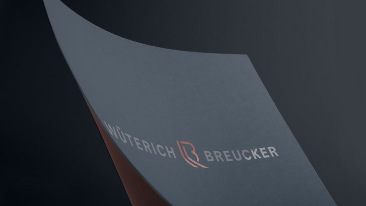 VISUELL Kommunikationsdesign: Corporate Design: Nahaufnahme der mit Heißprägefolie veredelten Wort-Bild-Marke auf dunkelblauem Papier