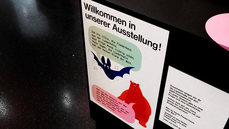 VISUELL Szenografie: Jubiläumsausstellung: 70 Jahre Fernsehturm und Liederhalle: Eine Station der Kinderbegleitausstellung mit Illustrationen an der Seite eines Bogentisches