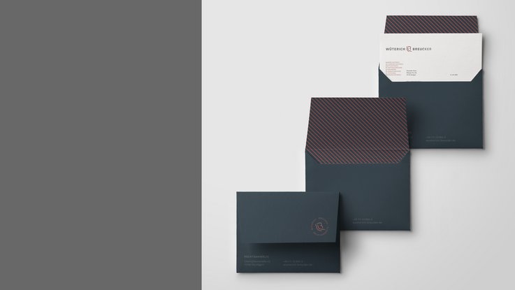 VISUELL Kommunikationsdesign: Corporate Design: Drei dunkelblaue Briefumschläge mit bronzefarbenen Linien auf der Innenseite sowie Briefbogen in einem der Umschläge