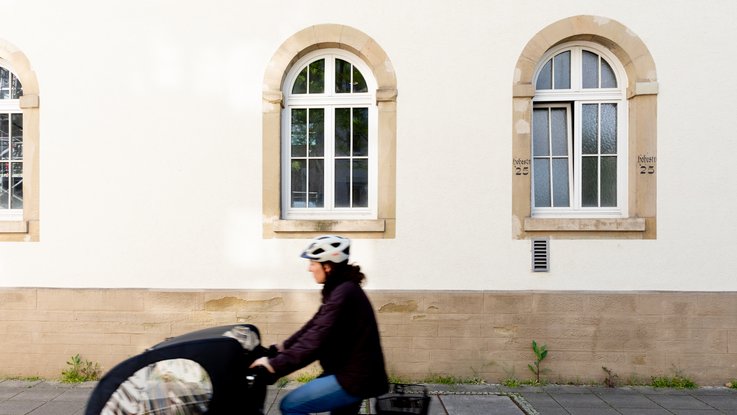VISUELL Kommunikationsdesign: Wandgrafiken Landeshauptstadt Stuttgart: Außenansicht eines Gebäudes mit vorbeifahrender Radfahrerin als Sinnbild für Bewegung, Alltag und urbane Infrastruktur.